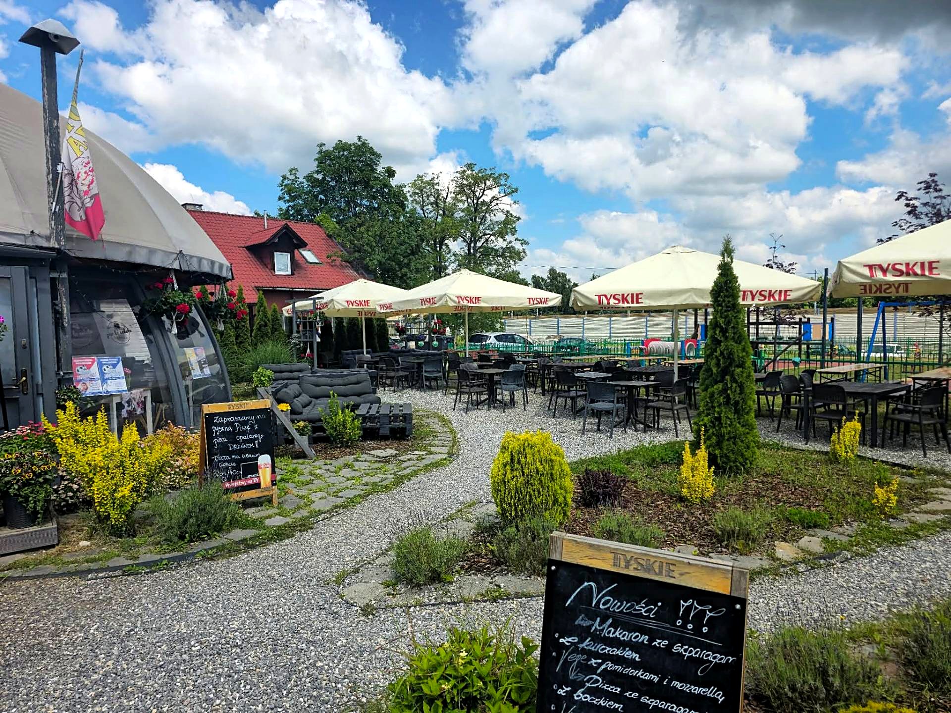 Ogród restauracji Oranżeria Per La Salute z parasolami i stolikami